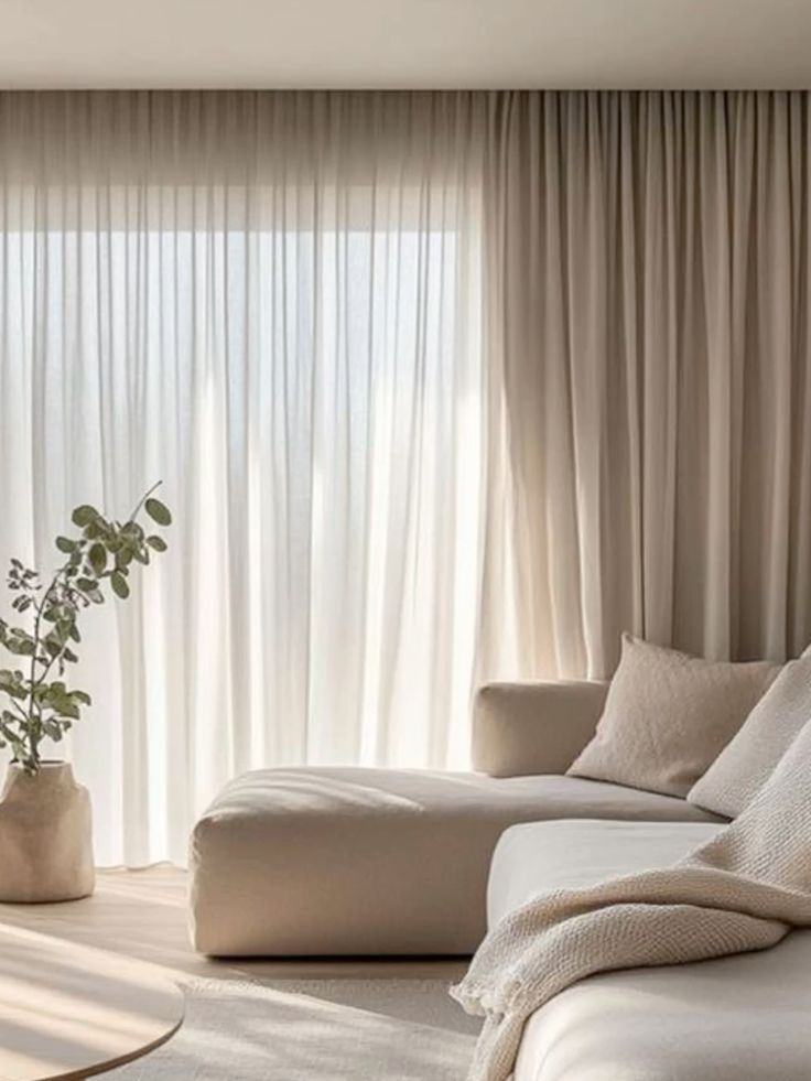Cortina franzida em tecido leve, com cortinado bege ao lado, numa sala com sofá claro