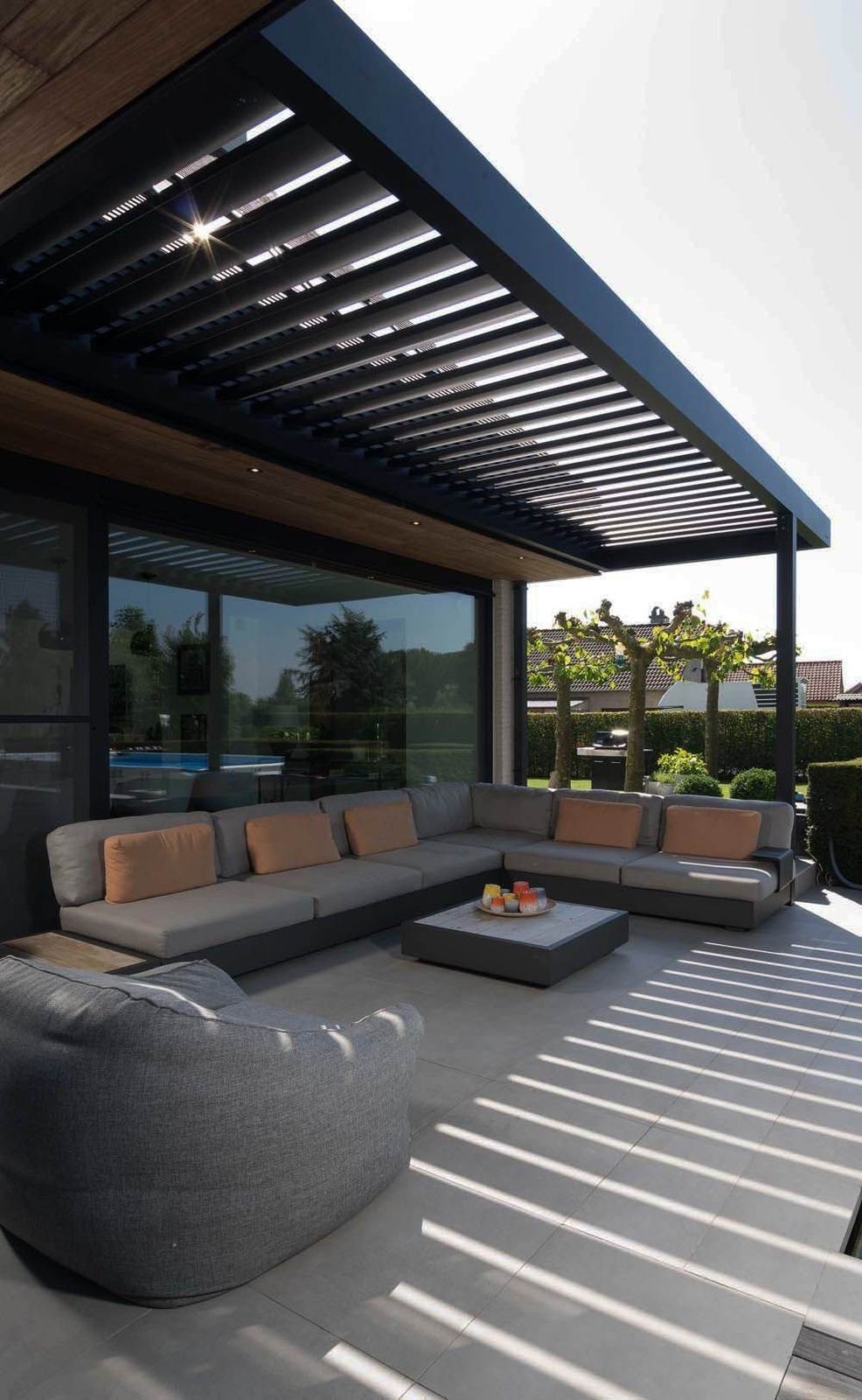 Pérgola bioclimática de lâminas orientáveis em antracite, com o sol a desenhar riscas no terraço
